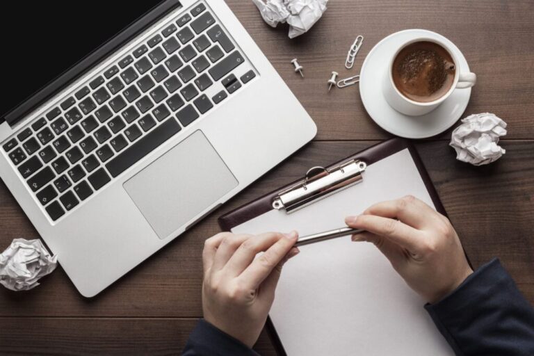Hands planning content strategy using clipboard and laptop