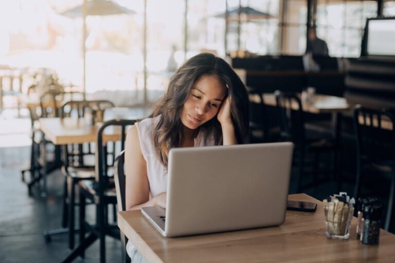 Woman brainstorming thought leadership content ideas at a cafe laptop