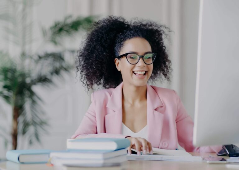 Professional woman smiling while creating thought leadership content at her desk