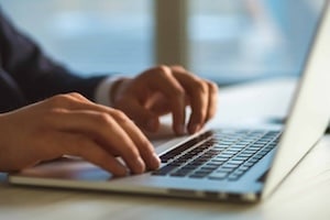 The hands typing on the laptop keyboard