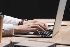 cropped view of seo manager sitting at table and using laptop