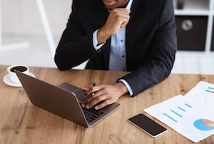 Cropped of black businessman working with laptop, reading marketing report