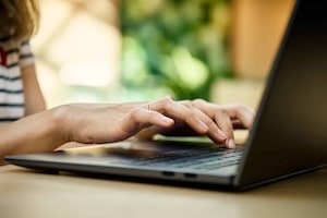 Female hands typing on laptop keyboard.