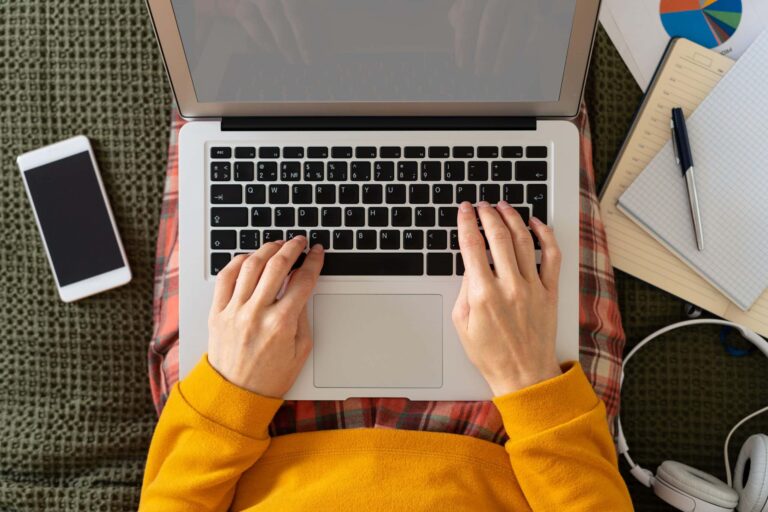 Person writing long-form blog content with laptop and notes