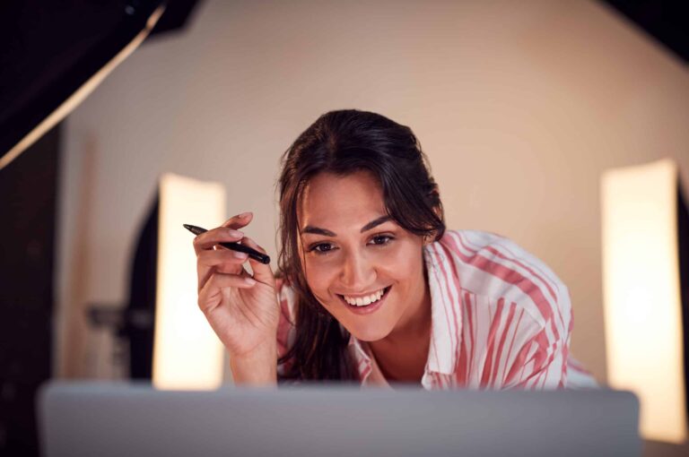 Smiling woman creating content strategy on a laptop with studio lights