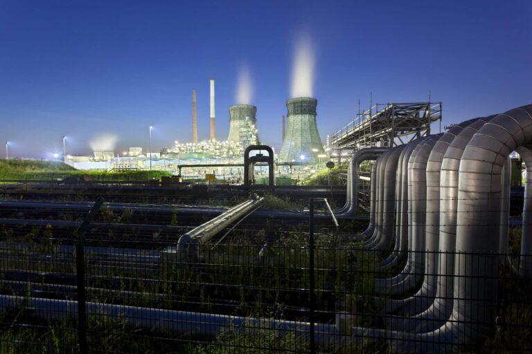 Industrial energy facility with cooling towers and steam under twilight sky