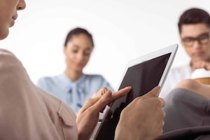 cropped shot of businesswoman using digital tablet while her colleagues working