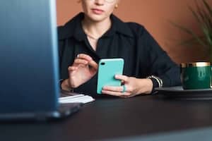 Professional planning monthly marketing posts using phone and laptop