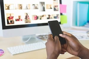 Rear view of young African-American graphic designer using mobile phone