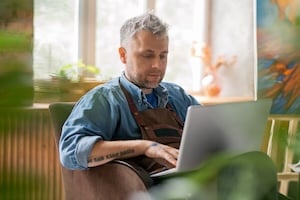 Local business owner creating small business marketing strategy on laptop from home workspace