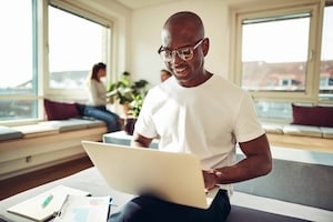 Smiling African businessman working online with colleagues in the background