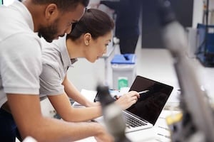 Two Engineers Using CAD Programming Software On Laptop