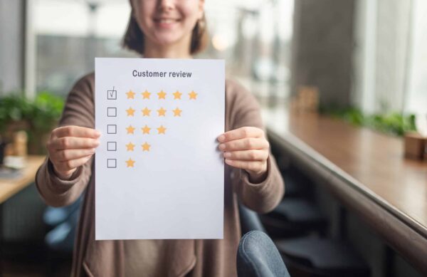 Woman holding paper with five-star customer review