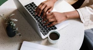 consultant updating website on laptop while drinking coffee