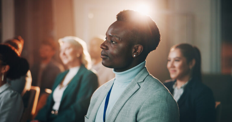 Confident business professional listening intently at an event, symbolizing the power of brand authority and industry recognition