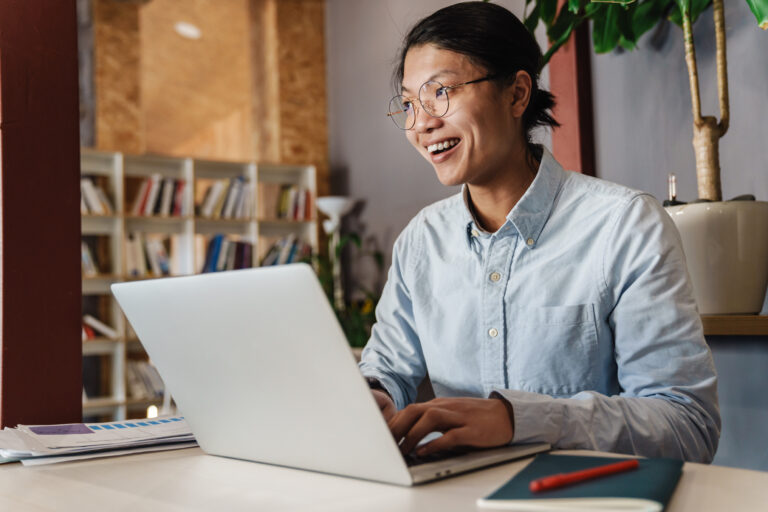 Smiling professional working on laptop in a bright office, symbolizing confidence and expertise in an online presence