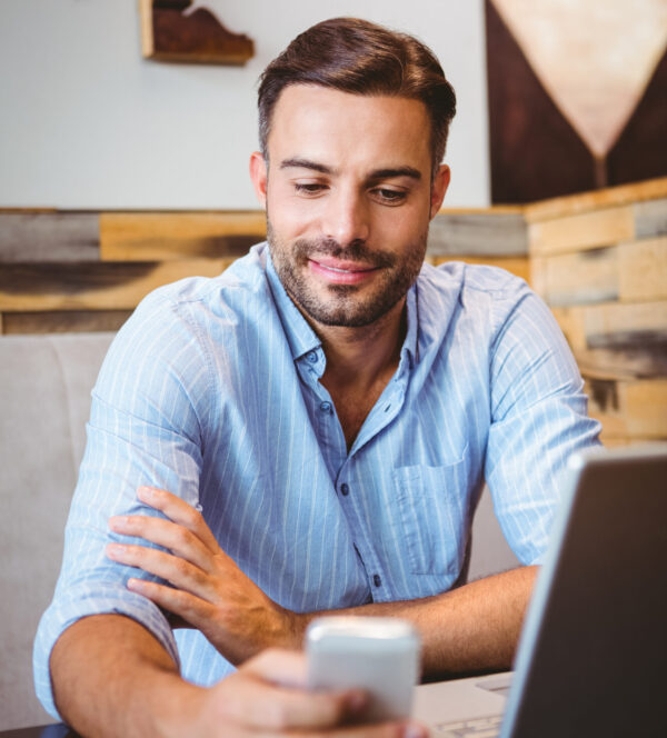 Man evaluating digital first impressions on phone and laptop
