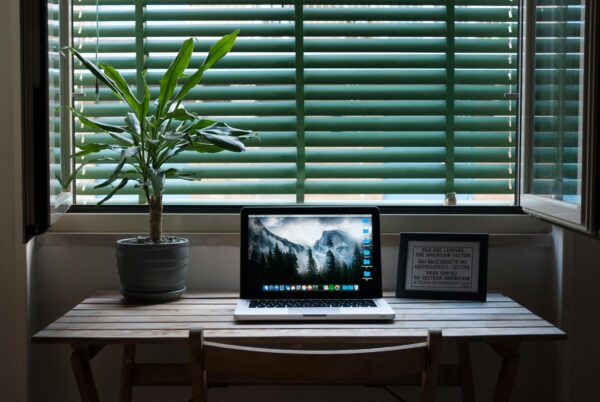 Laptop on a minimalist desk by a window, reflecting clean design and calming color tones for trustworthy website branding