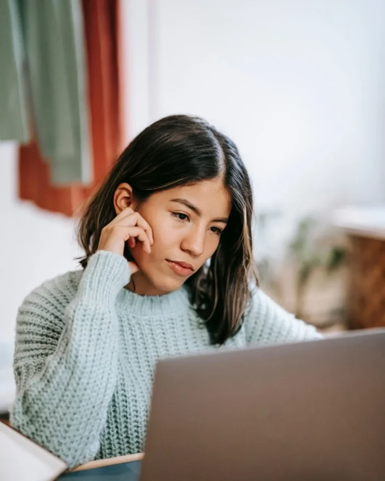 Woman thinking critically while browsing website content on laptop