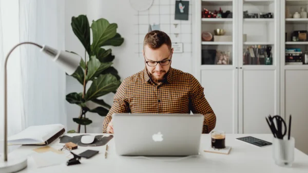 Man in glasses focused on laptop at a modern desk, representing thoughtful content work to optimize AI search results