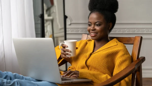 Woman sitting comfortably with coffee and laptop, using AI search to find answers