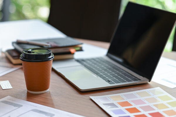 Workspace with laptop, color swatches, and a coffee cup—ideal setting for website content reviews and design updates.