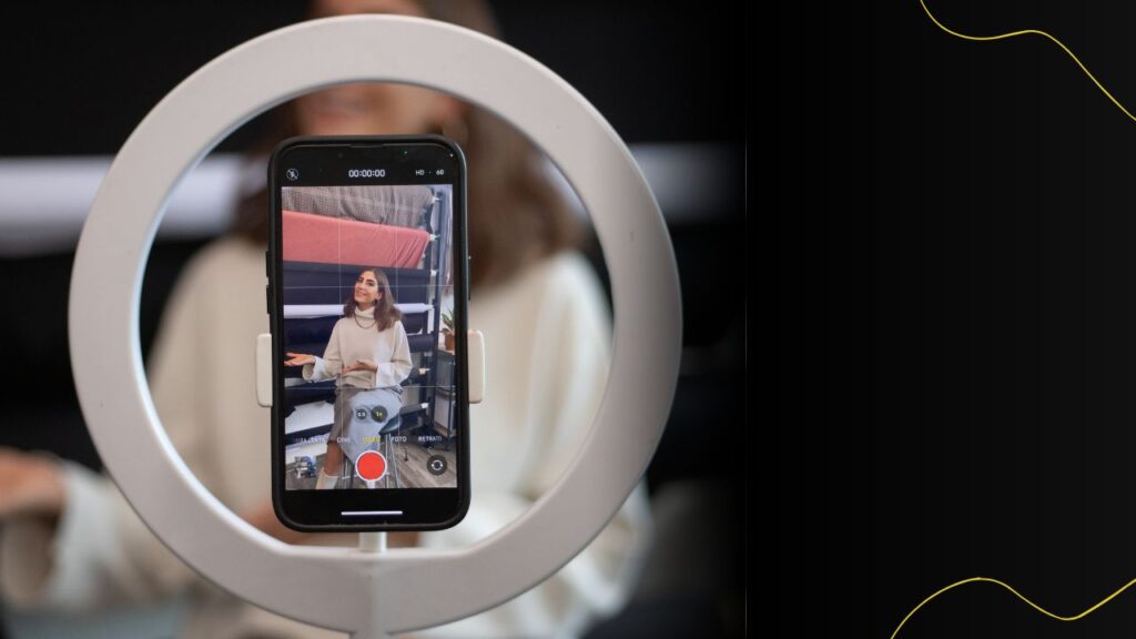 A content creator records a video using a smartphone and ring light, showing how consistent video creation supports a video SEO strategy.