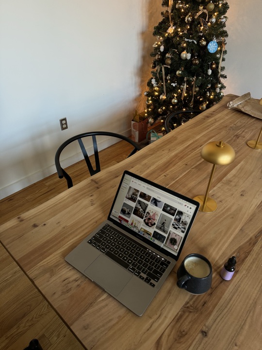 business owner laptop sitting on table preparing to update website for the holiday season. Christmas tree in corner with a festive feel.