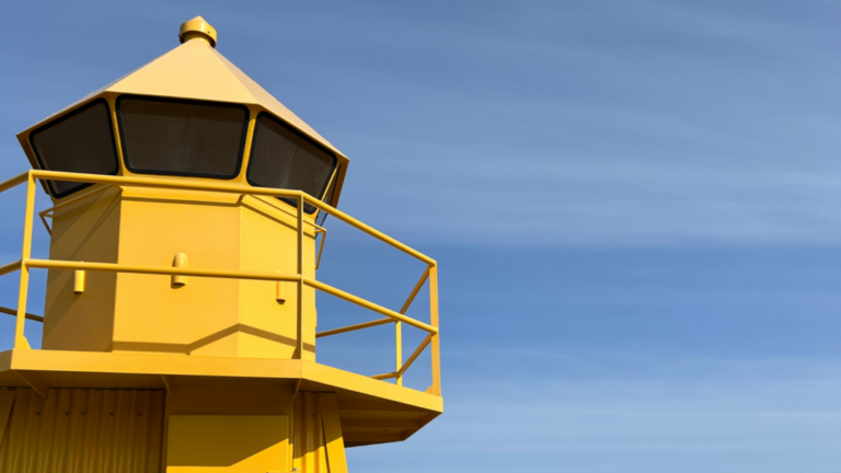 Yellow lighthouse against blue sky symbolizing visibility and leadership