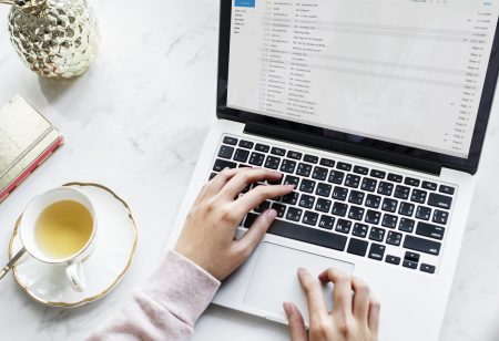 Aerial view of woman using a computer laptop and a cup of tea email