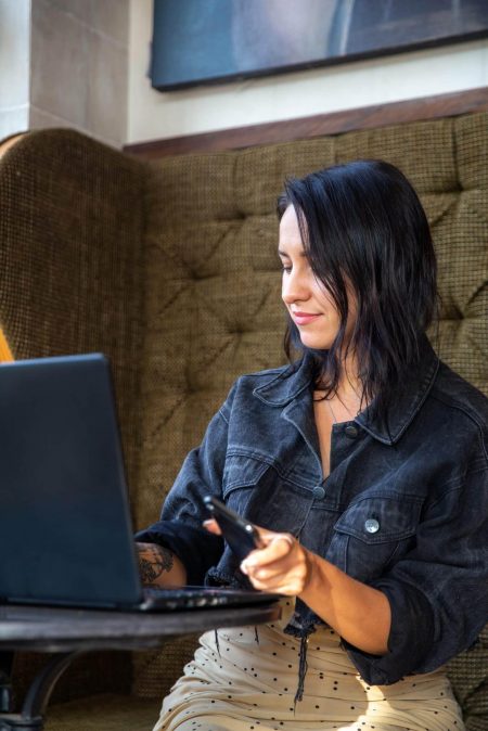 Portrait of smiling young woman using laptop and talking by mobile phone. concept of online job