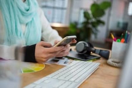 Female graphic designer using mobile phone at desk