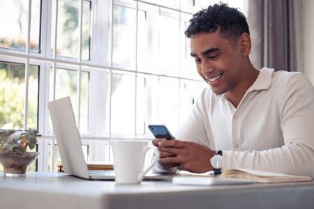 Shot of a young male using his cellphone at home. email