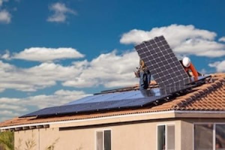 Workers Installing Solar Panels on House Roof.