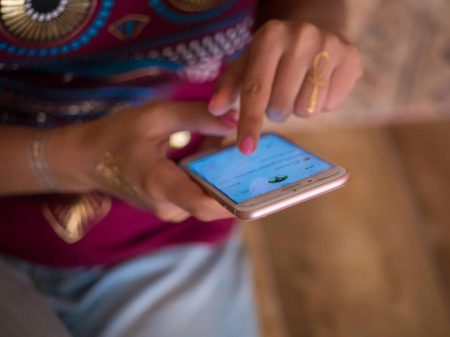 Woman scrolling through Instagram feed on smartphone with henna design on hand